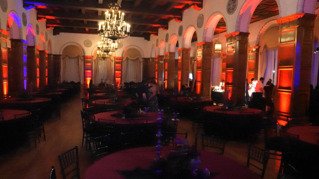 Round tables fill a chandelier-lit reception room prepared for the Google Holiday Party.