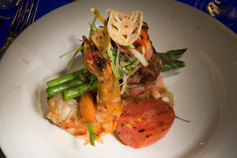 A plated seafood entrée is garnished with vegetables and herbs on a white plate.