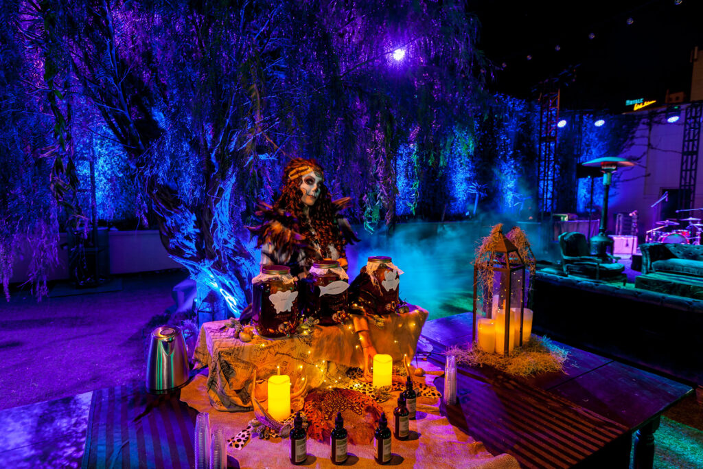 Guests gather around a candlelit table in a blue- and purple-lit event space.
