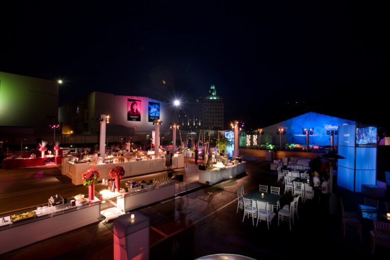Disney branded outdoor evening reception with illuminated food stations, screens and guests networking under string lights, photographed in Los Angeles.