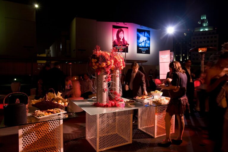 Disney branded networking lounge with a large red rose floral centerpiece, branded screen and guests mingling, photographed in Los Angeles.
