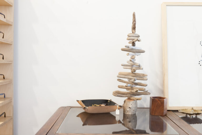 Sculptural stacked natural materials and framed artwork arranged on a table in a bright room.
