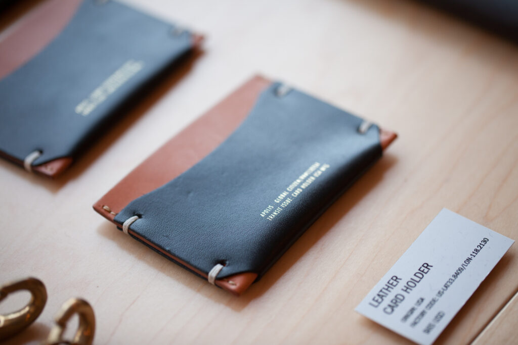 Two slim leather card holders in blue and rust tones placed beside a small printed product card.