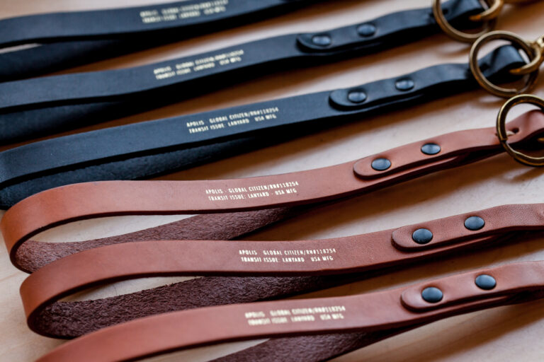 Several brown and black leather straps or belts with metal rings and branded tabs arranged diagonally on a table.