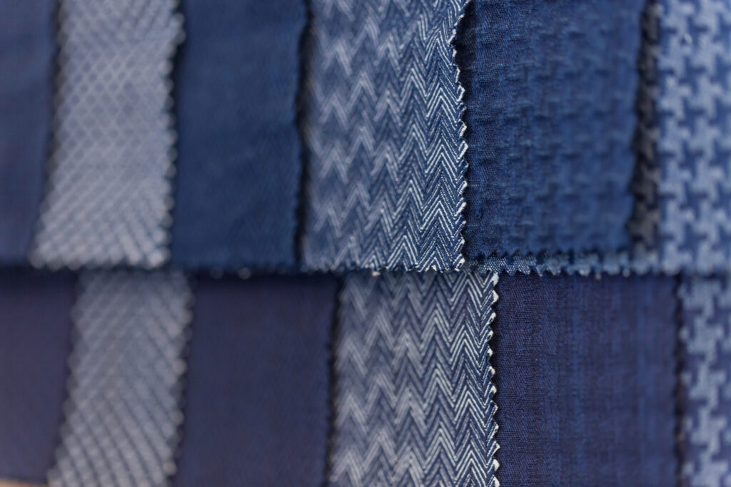 Close-up of overlapping blue and gray fabric swatches showing woven textures and zigzag patterns.