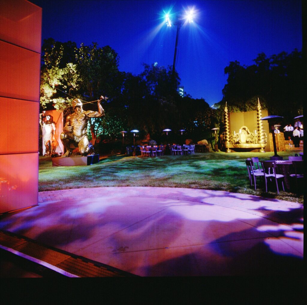 Outdoor evening event installation with green and purple theatrical lighting.